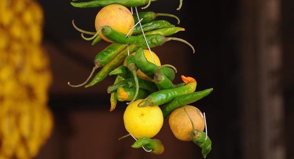 Lemons and green chillies strung together on a thread, hanging in a doorway